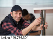 serviceman securing metal worktop support. Стоковое фото, агентство Ingram Publishing / Фотобанк Лори