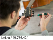 close up of man using a screw driver on guitar. Стоковое фото, агентство Ingram Publishing / Фотобанк Лори