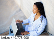 A young woman sits against a wall outdoors, focused on her laptop, embodying modern worklife balance. The tranquil setting boosts her creativity and productivity, enabling her to thrive. A Focused Young Woman is Quite Intently Working on Her Laptop While Enjoying the Outdoors. Стоковое фото, агентство Ingram Publishing / Фотобанк Лори