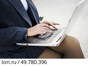 A professional woman in a sharp business suit types on her laptop outdoors, illustrating the blend of technology and professionalism, and showcasing her dedication and focus in the digital age. A professional woman types on her laptop outdoors, showcasing her vibrant career and confidence. Стоковое фото, агентство Ingram Publishing / Фотобанк Лори