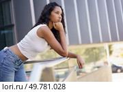 A young woman stands gracefully leaning on a railing, appearing deeply lost in her thoughts, while showcasing a stylish and chic outfit that complements the vibrant urban setting around her. A contemplative young woman is posing thoughtfully outdoors in an appealing and beautiful setting. Стоковое фото, агентство Ingram Publishing / Фотобанк Лори