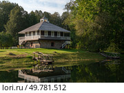 House-Museum of A. P. Hannibal with a reflection in the pond in the Petrovskoye estate of the natural landscape Reserve of A. S. Pushkin on a sunny summer day, Pushkinskiye Gory, Pskov region, Russia. Стоковое фото, фотограф Ula Ulachka / Фотобанк Лори