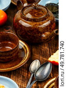 Modern style tea pot with tangerines tea and ripe fruits on rustic wooden table.. Tangerine tea in a glass teakettle. Стоковое фото, агентство Ingram Publishing / Фотобанк Лори