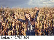 In a vibrant cornfield under golden sunlight, a joyful young woman dances with her arms raised, radiating happiness and freedom through her energetic, playful movements, spreading positivity. A Joyful Woman is Joyfully Dancing in a Beautiful Lush Cornfield Beneath a Bright Sunny Sky. Стоковое фото, агентство Ingram Publishing / Фотобанк Лори