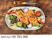 Raw uncooked salmon slices seasoned with lemon, spices, sauces and herbs. Marinated salmon on rustic wooden table.. Ingredients for baked salmon. Стоковое фото, агентство Ingram Publishing / Фотобанк Лори