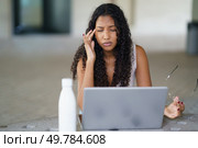 A young woman visibly exhibits signs of stress and anxiety while she works diligently on her laptop, highlighting the various challenges and pressures that come with remote work environments. A Stressed Woman Struggling While Working on Laptop in Contemporary Modern Workspace. Стоковое фото, агентство Ingram Publishing / Фотобанк Лори