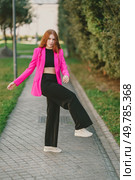 A poised model showcases a trendy pink blazer with stylish black trousers, exuding flair as she walks gracefully along a scenic path that complements her glamorous outdoor appearance. A vibrant fashion shot of a model in a stylish pink blazer and trendy black pants. Стоковое фото, агентство Ingram Publishing / Фотобанк Лори