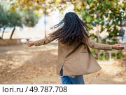 In a beautiful, serene outdoor setting, a woman with lovely, curly hair twirls joyfully, radiating happiness and freedom, while surrounded by vibrant autumn leaves and lush greenery all around her. A Joyful Woman Twirling in the Beautiful Outdoors Surrounded by Natures Splendor. Стоковое фото, агентство Ingram Publishing / Фотобанк Лори