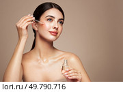 Young beautiful woman applying face serum with pipette. Cosmetic procedures for facial skin care. Стоковое фото, агентство Ingram Publishing / Фотобанк Лори