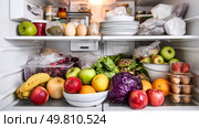 A refrigerator overflowing with unnecessary food items. Symbol of a major environmental problem caused by urban overconsumption waste. Abstract image. Стоковое AI-изображение, AI-художник ALLA YURTAYEVA / Фотобанк Лори