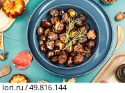 Cracked roasted chestnuts, roasted chestnuts some chestnuts split open , garnished with fresh rosemary, styled with autumn leaves.. Warm roasted chestnuts served on a plate. Стоковое фото, агентство Ingram Publishing / Фотобанк Лори