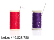 Two red and purple thread bobbin and needle isolated on white background. Стоковое фото, агентство Ingram Publishing / Фотобанк Лори