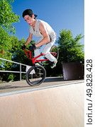 Bmx stunt performed at the top of a quarter piper ramp on a skatepark. Стоковое фото, агентство Ingram Publishing / Фотобанк Лори