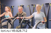Group of people engaged in a spin bike simulator in the gym, exercising on a stationary bike. Стоковое видео, видеограф Яков Филимонов / Фотобанк Лори