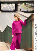 A Seven-Year-Old Girl Stands Gracefully on a Staircase Leading to a Bustling Street. Стоковое фото, фотограф Aleksandr Golubev / Фотобанк Лори