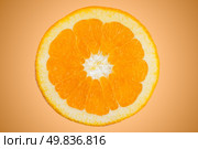 Closeup of orange slice on orange gradient background. Стоковое фото, агентство Ingram Publishing / Фотобанк Лори