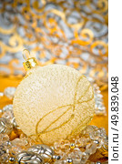 Golden christmas ball with decorations on golden surface and blured backdrop. Стоковое фото, агентство Ingram Publishing / Фотобанк Лори