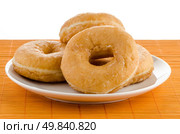 Closeup of donuts on a plate on orange straw mat background. Стоковое фото, агентство Ingram Publishing / Фотобанк Лори