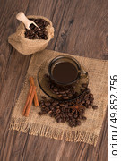 Coffee cup with burlap sack of roasted beans on rustic table. Стоковое фото, агентство Ingram Publishing / Фотобанк Лори