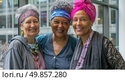 Three women of different ethnicities standing closely together outdoors in casual attire. Стоковое AI-изображение, AI-художник Данила Большаков / Фотобанк Лори