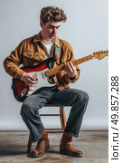 A man is seated on a chair, strumming a guitar with focused concentration. Стоковое AI-изображение, AI-художник Данила Большаков / Фотобанк Лори