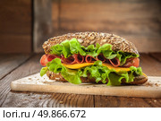 Sandwich on the wooden table with slices of fresh tomatoes, ham, cheese and lettuce. Стоковое фото, агентство Ingram Publishing / Фотобанк Лори