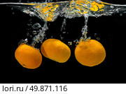 Fresh tangerines dropped into water with bubbles on black. Стоковое фото, агентство Ingram Publishing / Фотобанк Лори