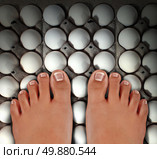 Walking on eggs as an emotional concept of anxiety and stress for treading carefully on a dangerous fragile path as a metaphor for challenges risk and security with barefoot human feet stepping on white eggshells. Стоковое фото, агентство Ingram Publishing / Фотобанк Лори
