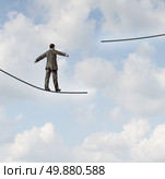 Difficult situation business concept with a businessman walking on a tightrope or high wire metaphor that has been cut and moved higher resulting in increased risk and danger to a planned strategy. Стоковое фото, агентство Ingram Publishing / Фотобанк Лори