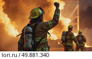 A woman in a firefighter's uniform raises her right arm in a fist pump after successful rescuing someone from a burning building. She signals her colleagues to start extinguishing the fire. Стоковое AI-видео, аниматор Sergey Grishin / Фотобанк Лори