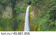 Tall waterfall pouring down mossy cliff into clear pool in Costa Rica. Стоковое видео, видеограф Igor Tichonow / Фотобанк Лори