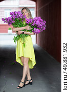A beautiful elderly woman with a bouquet of flowers walks through the streets of the city. Age model blonde in full growth. A woman in her fifties in a beautiful dress. Стоковое фото, фотограф Лазаренко Светлана / Фотобанк Лори