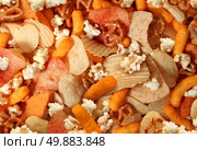 Snacks background with salty crunchy treats as potato chips and cheese flavored puffs fried or baked food as pretzels pop corn and nachos as a symbol of assorted party mix appetizer. Стоковое фото, агентство Ingram Publishing / Фотобанк Лори