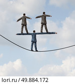 Business people manager concept as a businessman walking on a tight rope with two other businesspeople standing on the shoulders of the leader as a symbol of work support and career guidance. Стоковое фото, агентство Ingram Publishing / Фотобанк Лори
