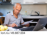 Senior man calculates profits and losses of online trading on calculator. Стоковое фото, фотограф Татьяна Яцевич / Фотобанк Лори