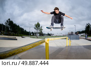 Skateboarder doing a ollie over the rail at the skate park. Стоковое фото, агентство Ingram Publishing / Фотобанк Лори