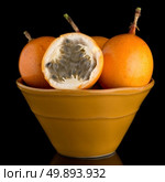 Passion fruit maracuja granadilla on ceramic yellow bowl, black background. Стоковое фото, агентство Ingram Publishing / Фотобанк Лори