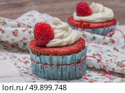 Red cupcakes with cream cheese frosting and raspberries  on white wooden table. Стоковое фото, агентство Ingram Publishing / Фотобанк Лори