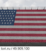 American border wall concept as a security barricade with a flag of the United States as a customs and country boundary barrier with barbed wire as a symbol for illegal immigration control as a 3D illustration. Стоковое фото, агентство Ingram Publishing / Фотобанк Лори