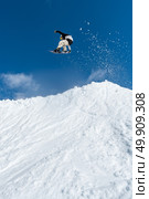 Snowboarder executing a radical jump against blue sky. Стоковое фото, агентство Ingram Publishing / Фотобанк Лори