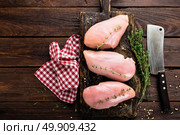 Raw chicken breasts fillets with thyme and spices on wooden cutting board on rustic background copy space directly above. Стоковое фото, агентство Ingram Publishing / Фотобанк Лори