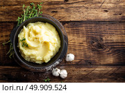 Mashed potatoes, boiled puree in cast iron pot on dark wooden rustic background, top view. Стоковое фото, агентство Ingram Publishing / Фотобанк Лори