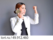 Asian Business woman holding a mobile phone successfully negotiated. Стоковое фото, агентство Ingram Publishing / Фотобанк Лори