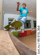 Skateboarder performing a frontside pivot grind on mini ramp at indoor skate park. Стоковое фото, агентство Ingram Publishing / Фотобанк Лори