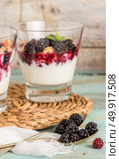 Yogurt desert with raspberries, blackberry and mint. Focus on spoons with blackberries. Стоковое фото, агентство Ingram Publishing / Фотобанк Лори