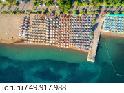 Aerial view of transparent turquoise sea, beautiful sandy beach with colorful chaise-lounges, boats, green trees at sunset in Icmeler,Turkey. Summer seascape. Top view from flying drone. Azure water. Aerial view of transparent turquoise sea. Стоковое фото, агентство Ingram Publishing / Фотобанк Лори