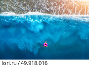 Aerial view of slim woman swimming on the pink swim ring in the transparent turquoise sea in Oludeniz,Turkey. Summer seascape with girl, beautiful waves, blue water in sunny day. Top view from drone. Стоковое фото, агентство Ingram Publishing / Фотобанк Лори
