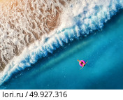 Aerial view of young woman swimming on the pink swim ring in the transparent blue sea in Oludeniz,Turkey. Summer seascape with girl, beautiful waves, azure water at sunset. Top view from drone. Travel. Aerial view of young woman swimming on the pink swim ring. Стоковое фото, агентство Ingram Publishing / Фотобанк Лори