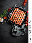 Grilled sausages bratwurst in grill frying-pan on black background. Top view. Traditional German cuisine. Stock image. Стоковое фото, агентство Ingram Publishing / Фотобанк Лори