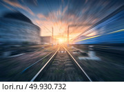 Railway station with motion blur effect. Blurred railroad. Industrial conceptual landscape with blurred railway station, speed train, blue sky with colorful clouds and sun. Railway track. Background. Railway station with motion blur effect. Blurred railroad. Стоковое фото, агентство Ingram Publishing / Фотобанк Лори